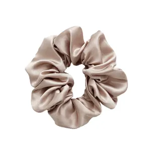 Elegant champagne satin oversized scrunchie with silk glossy texture on white background