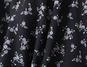 Macro detail of French vintage floral fabric with purple flowers on black woven base