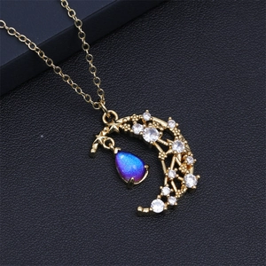 Macro detail of gold moon pendant with pavé crystals and purple teardrop gemstone