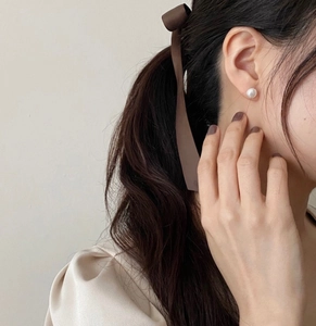 Close-up of elegant 925 silver stud earrings with high-luster white pearls on model