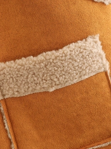 Detailed macro view of camel faux suede texture and creamy white sherpa lining on the vest