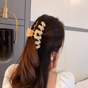Détail d'une grande pince à cheveux géométrique crème sur les cheveux d'un modèle