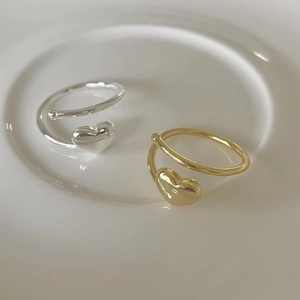 Detailed view of two minimalist heart-shaped open rings in gold and silver finish