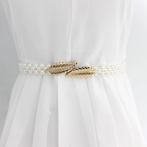 Detail of multi-row pearl elastic waist chain with golden leaf-shaped buckle on dress