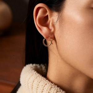 Macro side view of golden nail-shaped hoop earrings with micro-inlaid cubic zirconia