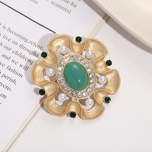 Seitenansicht einer Vintage-Brosche mit grünem Edelstein und Perlenbesatz