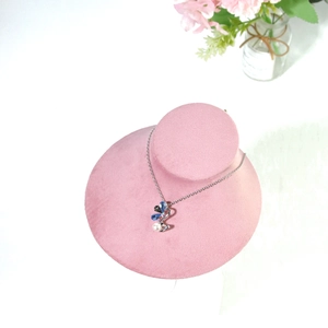 Detail of silver necklace with blue rhinestones and pearl on pink velvet display stand