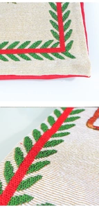 Detail of Santa pillow cover with red borders and green leaf embroidery on gold linen