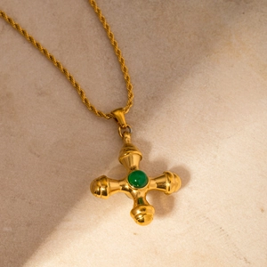 Close-up of 18k gold stainless steel cross necklace with a green gemstone inlay