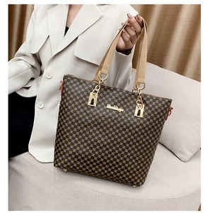 Detail of the brown patterned tote bag with beige handles and gold hardware details
