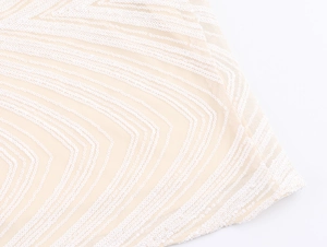 Macro detail of geometric white sequins and wavy embroidery on champagne mesh fabric
