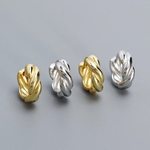 Detailed view of twisted rope hoop earrings in gold and silver finish on grey background