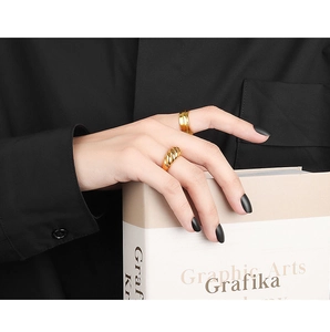 Close-up of golden croissant twist ring and layered band on a model's hand