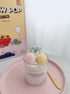 Detail of strawberry dessert scented candle with macaron and donut toppings in glass