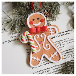 Close-up of a gingerbread man resin ornament with candy cane and snowy pine branch decor