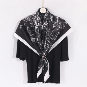 Détail d'un foulard en soie imprimé noir et blanc avec une boucle dorée élégante