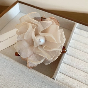 Détail de la pince à cheveux fleur en dentelle faite main avec perle sur plateau à bijoux
