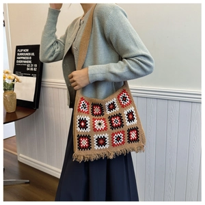 Detail of crochet tote bag featuring khaki granny squares with red tassels on shoulder