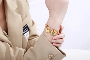 Macro detail of gold adjustable wire bracelet with Love and mi mama engraved charms