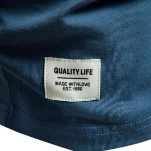 Close-up of blue cotton V-neck T-shirt showing hem tag with Quality Life embroidery