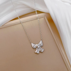 Macro shot of silver bow pendant with heart detail on titanium steel necklace