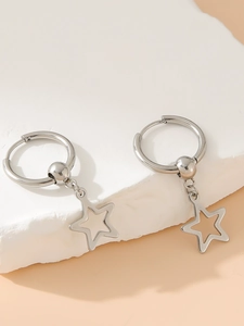 Detail of silver stainless steel earrings with hollow star charms on stone background