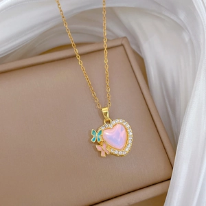 Close-up of golden heart pendant with pink stone and small butterflies on jewelry box