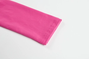 Detailed macro view showing the rose pink knit fabric texture and double-needle hem stitching