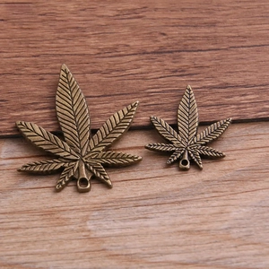 Antique bronze alloy maple leaf charms in two sizes on a textured wood background