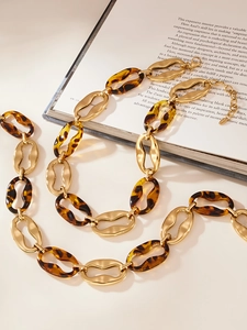 Detail of vintage chunky link necklace with gold metal and leopard resin loops on book
