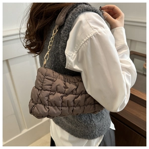 Détail du sac nuage matelassé marron foncé avec bandoulière chaîne dorée à l'épaule