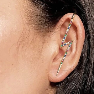 Detailed view of gold lighting bolt ear cuff with colorful crystals on human ear