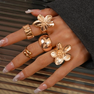 Detail of five-piece gold floral and textured rings set on fingers for women