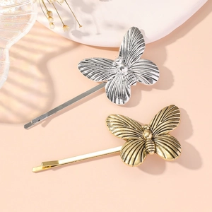 Elegant gold and silver butterfly hair clips displayed on a decorative stand