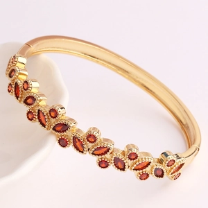 Detailed macro of 18K gold plated geometric cuff with marquise-cut red zircon stones