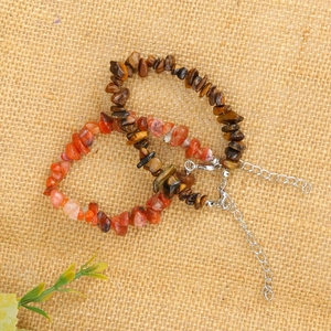 Detail view of natural tiger eye and red agate stone bracelets on rustic linen