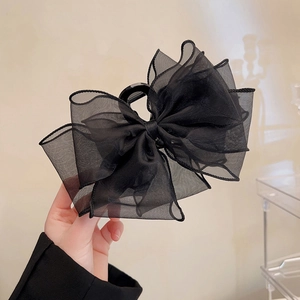 Detail view of large black organza layered bow hair claw clip held in hand