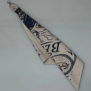 Detailaufnahme des beigen Baumwoll-Bandanas mit Vintage-Muster und Leder-Metallverschluss