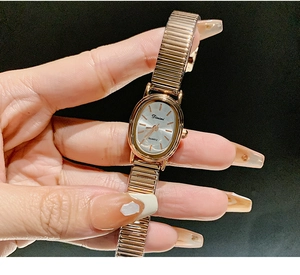 Close-up of rose gold elastic strap watch with white oval dial and gold markers
