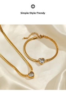 Detail of gold herringbone chain set with heart-shaped zircon pendant on white silk