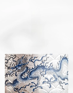 Detalle macro del patrón de dragón plateado hecho a mano en la taza de té de porcelana azul