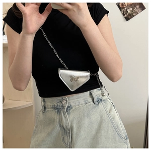 Silver triangle chain bag with metallic finish and bow decoration shown worn in mirror