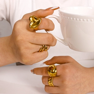 Irregular heart-shaped gold plated titanium steel rings on model holding a white cup