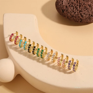 Créoles dorées serties de zircons colorés sur un présentoir de bijoux élégant