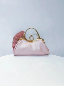 Detail of pink satin evening clutch with pleated fan design and golden metal handle