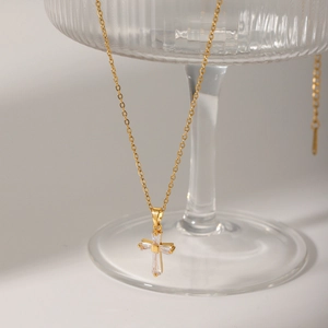 18K gold plated stainless steel cross necklace with cubic zirconia pendant on glass stand