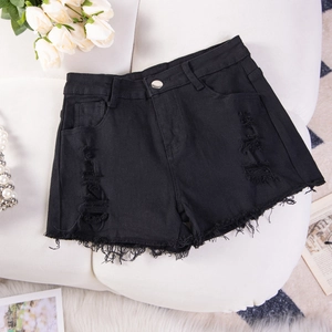 Pantaloncini di jeans neri strappati con dettagli usurati e orlo sfrangiato su divano bianco