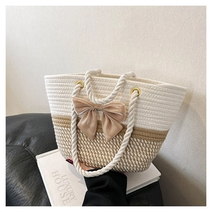 Detail of hand-woven tote bag featuring a large satin bow and thick rope handles