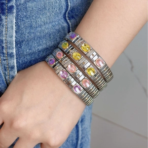 Set of four stainless steel stretch bracelets with colorful oval gemstones on female wrist
