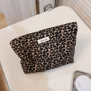Close-up of leopard print canvas makeup bag on a bathroom counter with accessories